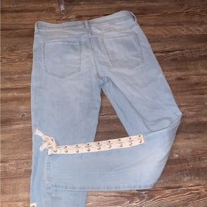 Blue jeans pants with white yarn on the bottom pants leg.